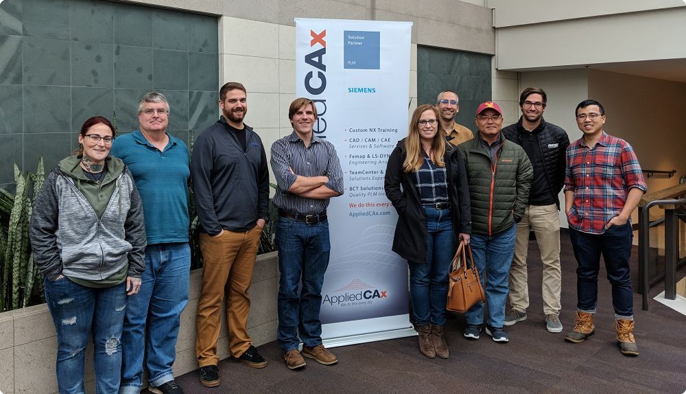 Nine people smiling at the camera in a training center - Applied CAx Siemens software partner USA