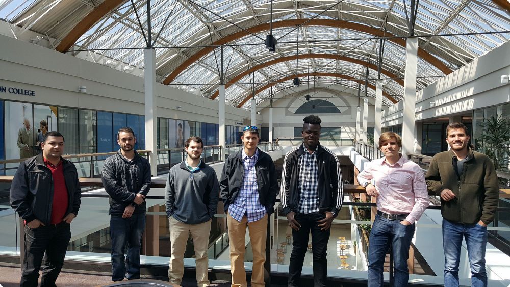 Group of seven men smiling and standing in a mall - Applied CAx Siemens software partner USA femap training