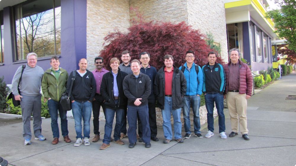 Group of 12 men smiling and standing outside a building - Applied CAx Siemens software partner USA