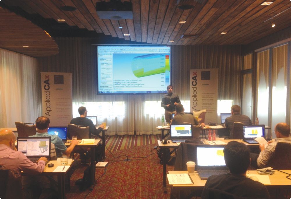 Group of people in a clasroom with a Femap tutorial on the board at the front of the room - Applied CAx Siemens software partner USA