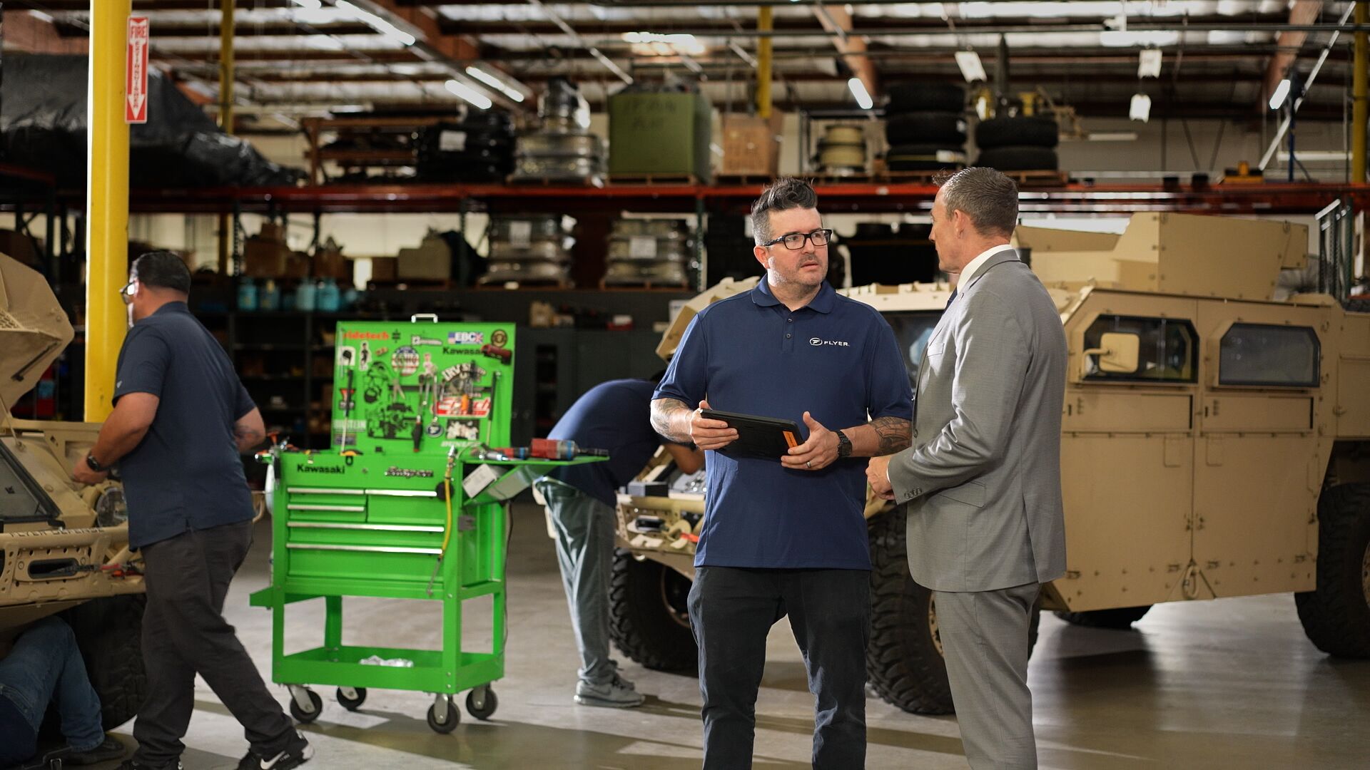 Two men from flyer defense talking in a warehouse - Applied CAx Siemens software