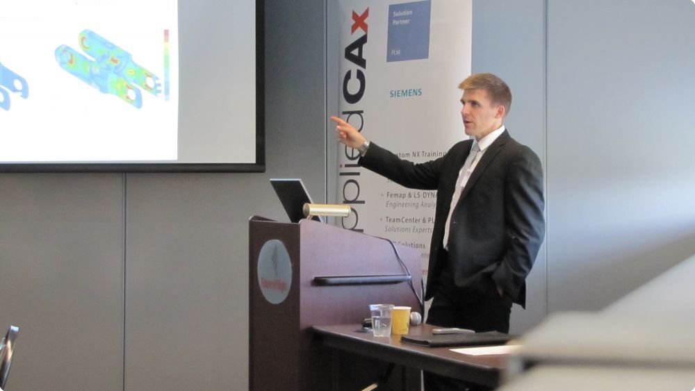 Man presenting in a classroom pointing to the board with Femap tutorial on screen - Applied CAx Siemens software partner USA