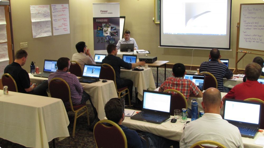 Group of people sit in a classroom with Femap tutorial on the board at the front of the room - Applied CAx Siemens software partner USA