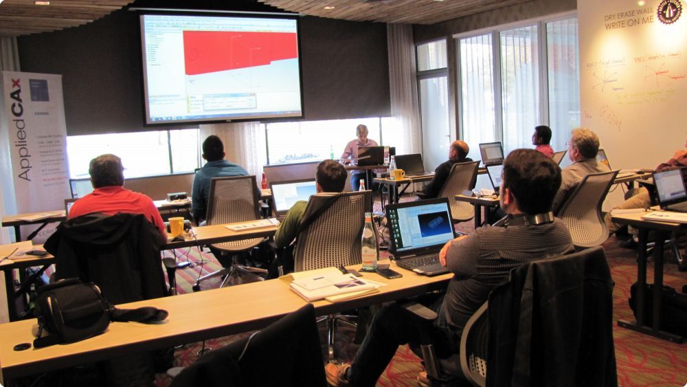 People sit in a classroom with a tutorial video on the board - Applied CAx Siemens software partner USA