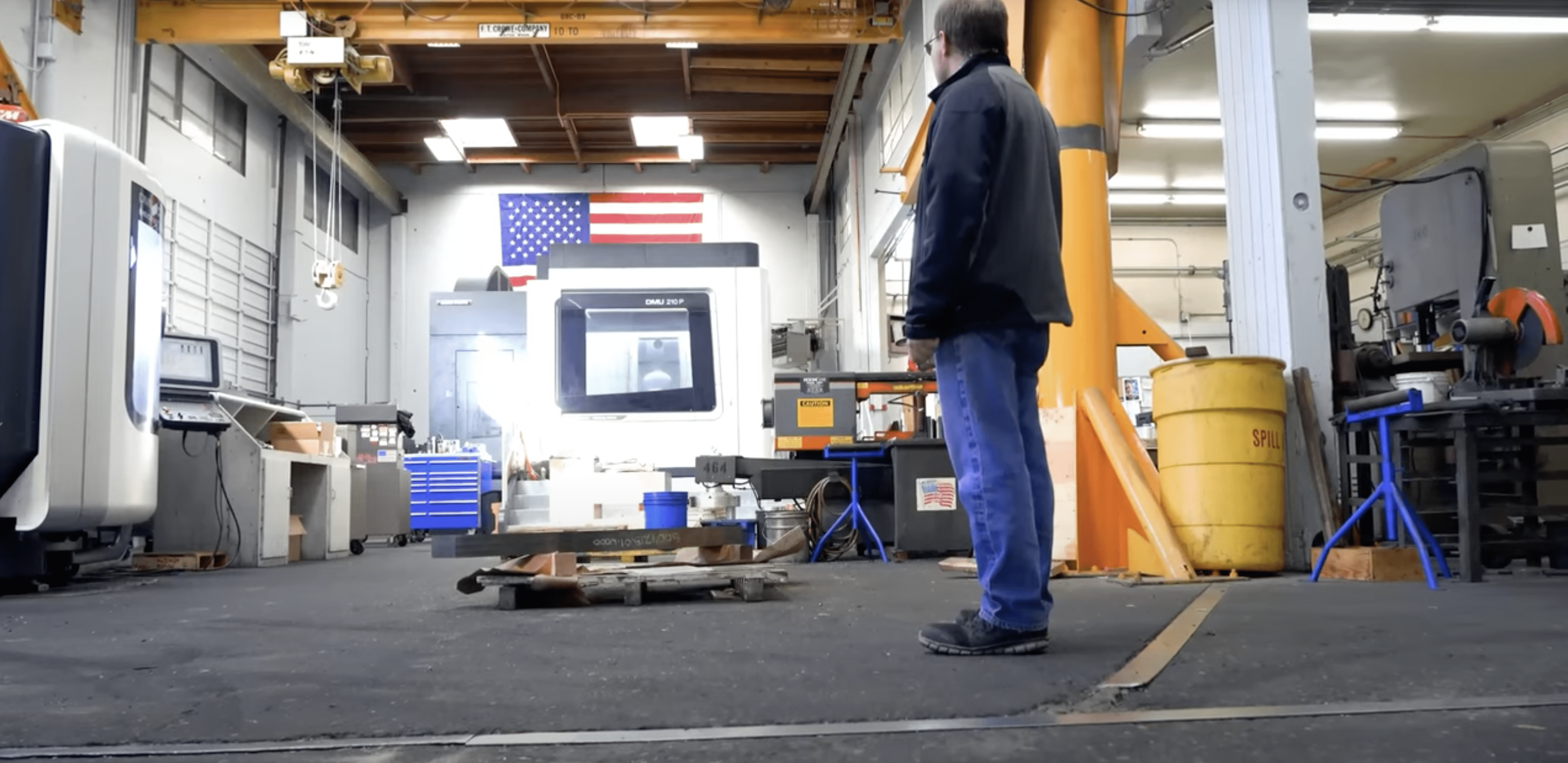 man standing in a warehouse looking toward a machine - Applied CAx Siemens software partner USA